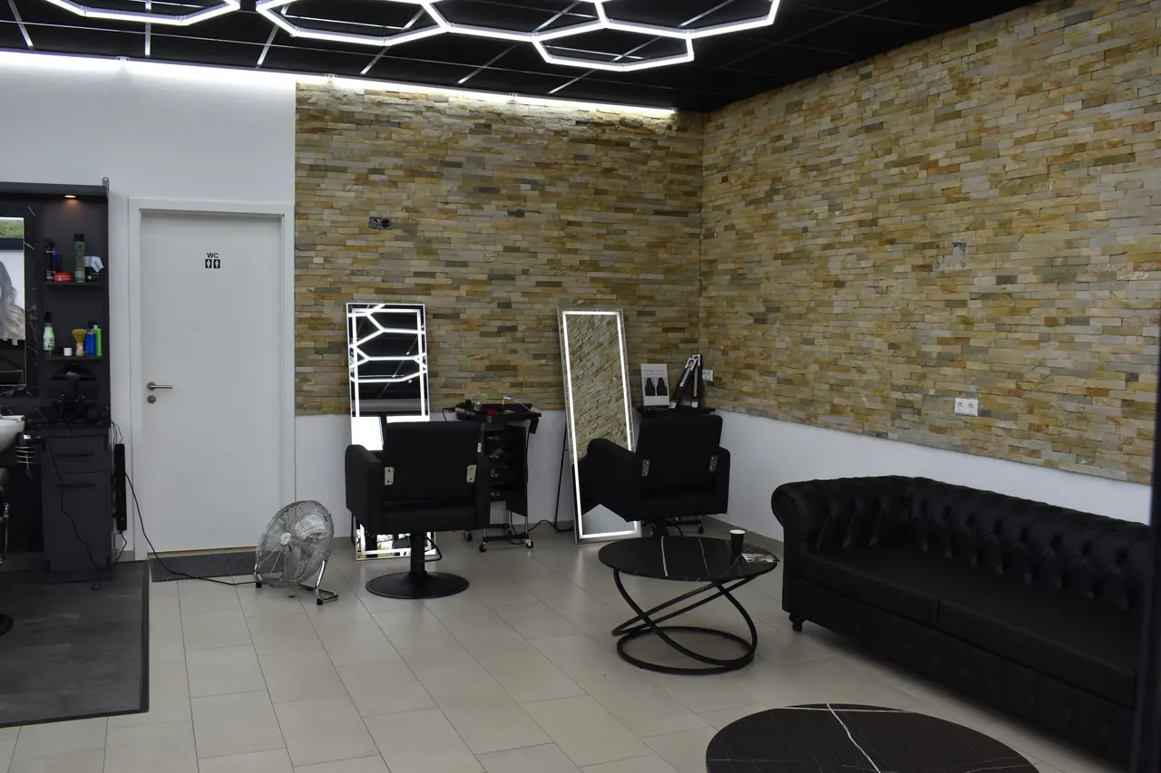 Lounge im JM Salon mit Steinwand, Ledersofa und beleuchteten Spiegeln